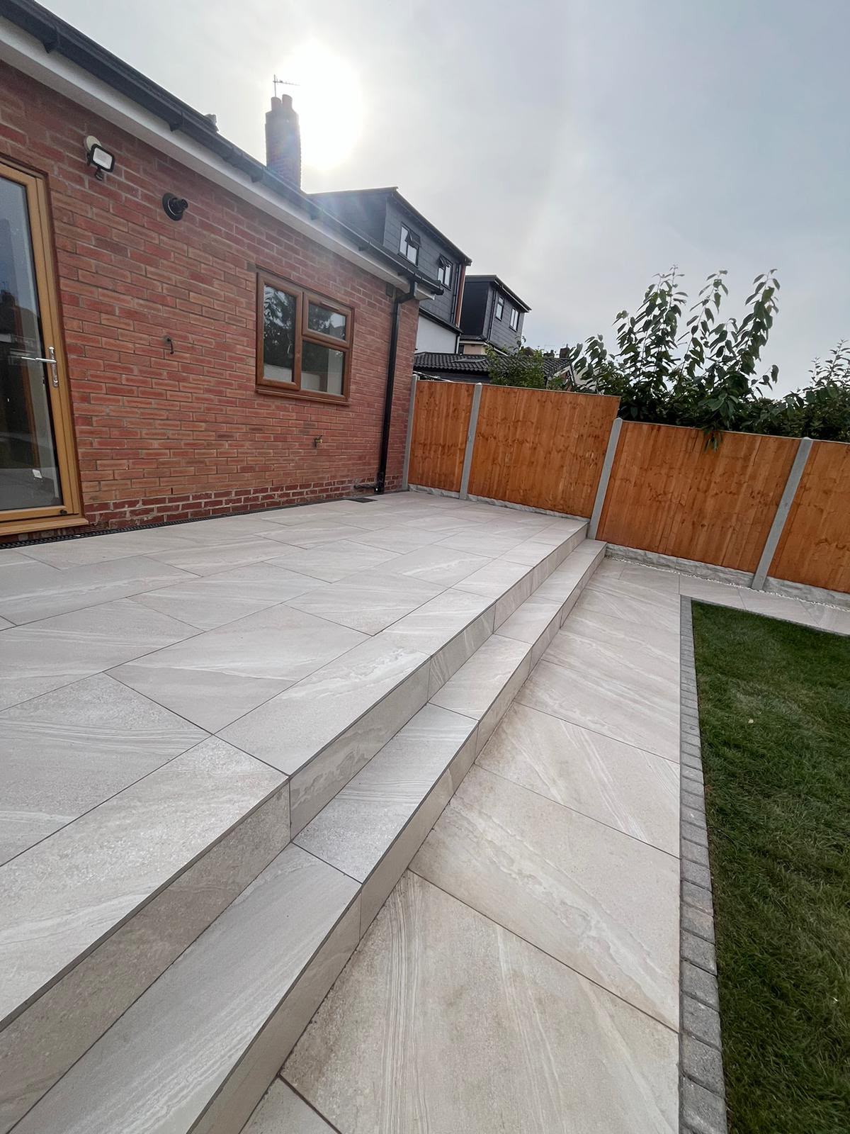 Grey porcelain patio in stack bond pattern running the length of a UK back garden